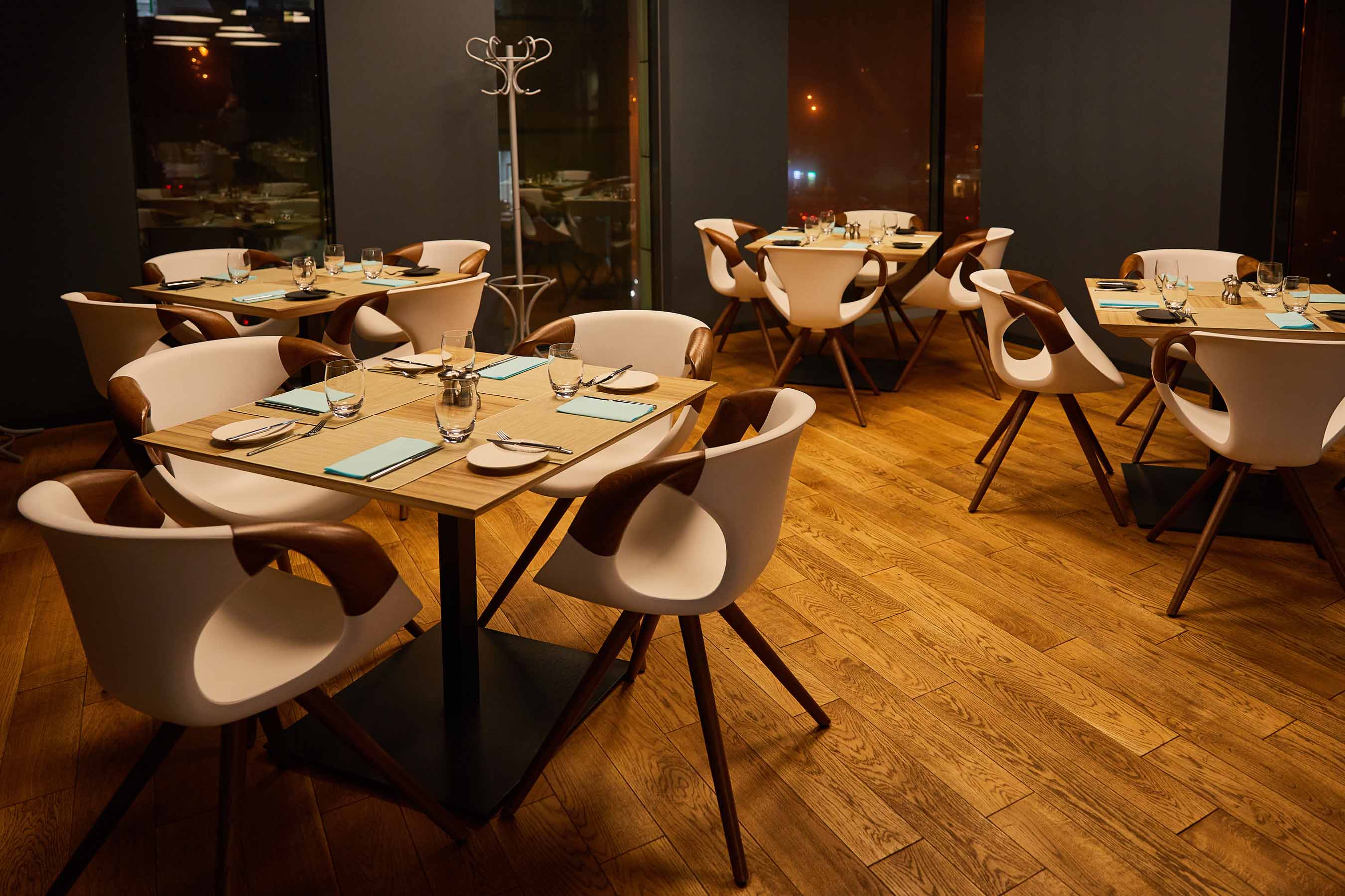 Salle de restaurant contemporain avec parquet en bois, murs foncés et éclairage chaleureux
