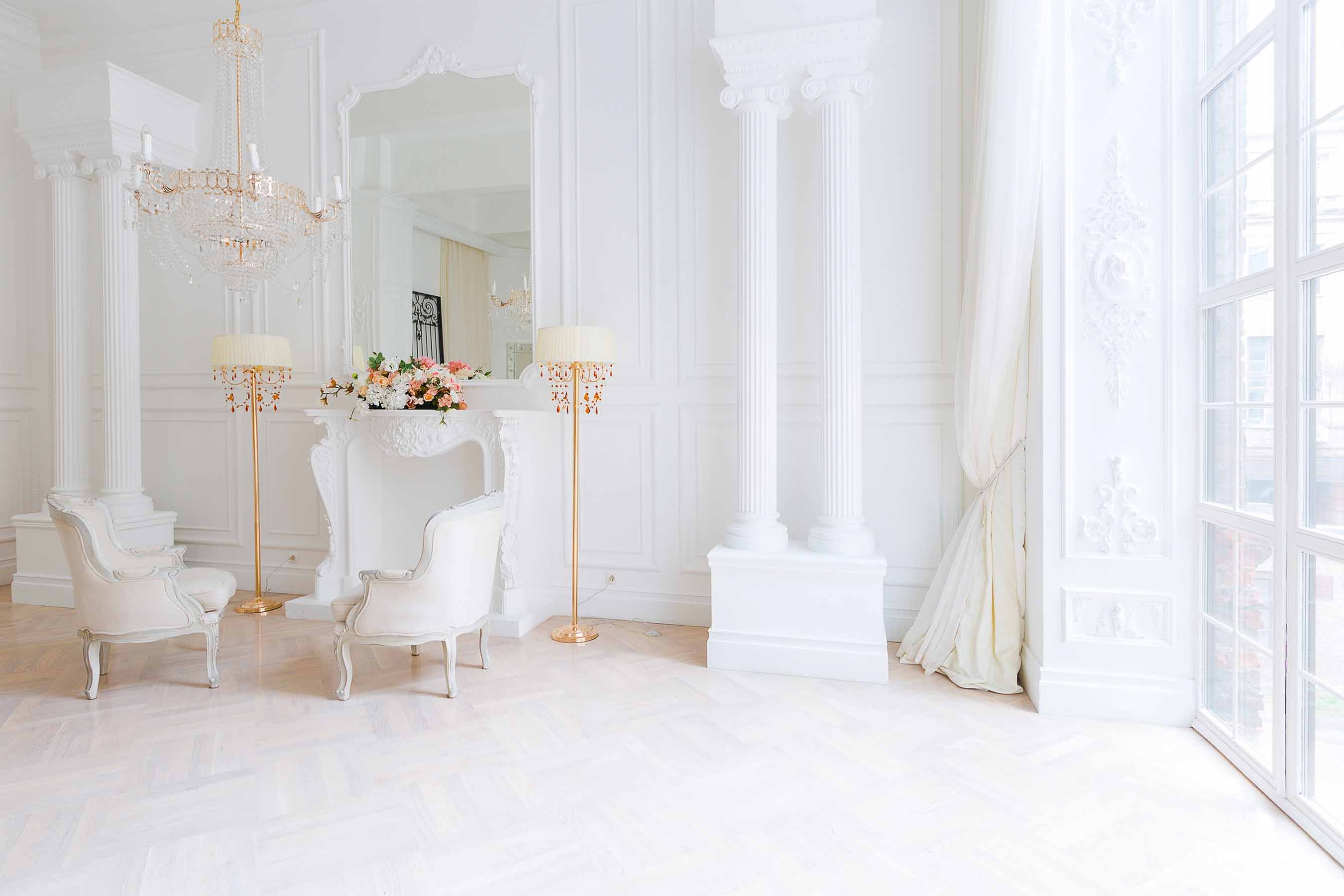 Salon élégant aux murs blancs avec moulures décoratives, colonnes et cheminée classique